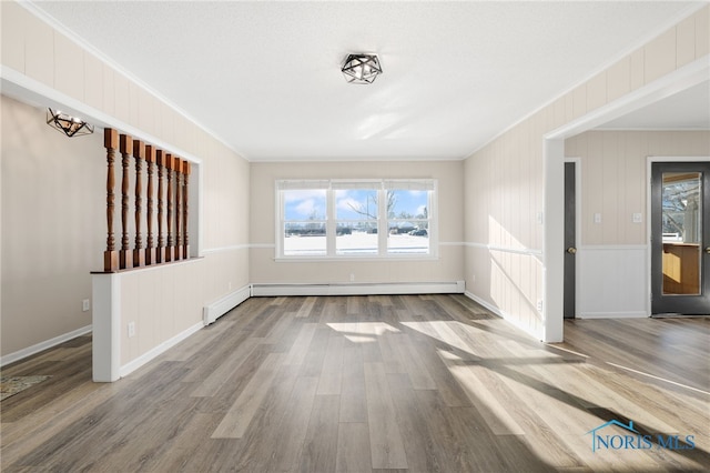 interior space with crown molding, a baseboard heating unit, and hardwood / wood-style flooring