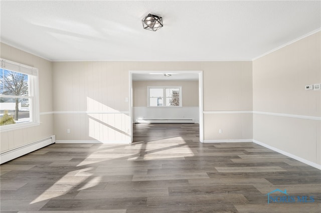 unfurnished room with dark wood-type flooring, a baseboard radiator, and a wealth of natural light