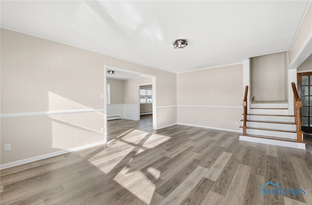 unfurnished living room featuring crown molding, a baseboard radiator, and wood-type flooring