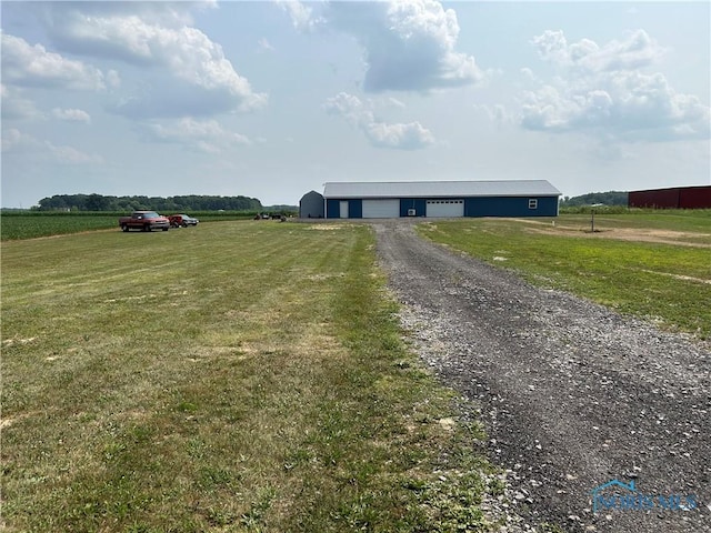 view of front of property featuring a garage, a front yard, and a rural view