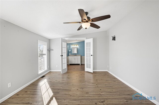 unfurnished bedroom featuring dark hardwood / wood-style flooring, ceiling fan, and french doors