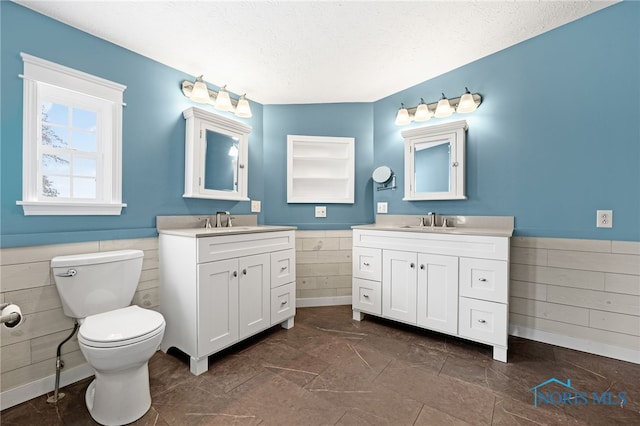 bathroom with vanity, tile walls, a textured ceiling, and toilet