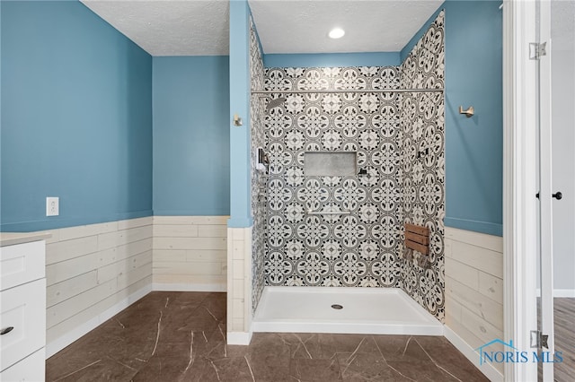 bathroom with vanity, a tile shower, and a textured ceiling