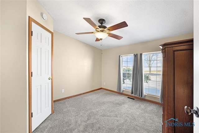 carpeted spare room featuring a textured ceiling and ceiling fan