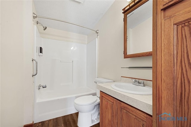 full bathroom featuring shower / washtub combination, hardwood / wood-style flooring, vanity, toilet, and a textured ceiling