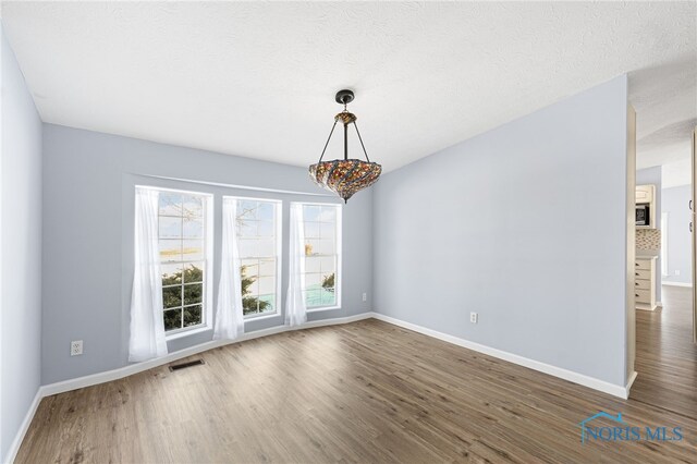 unfurnished room with dark wood-type flooring and a textured ceiling