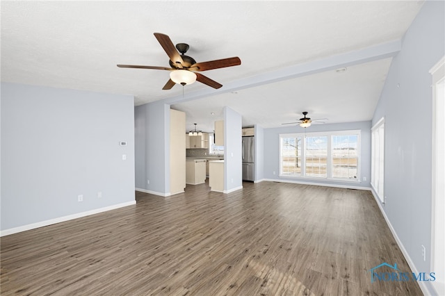 unfurnished living room with lofted ceiling with beams, dark hardwood / wood-style floors, and ceiling fan