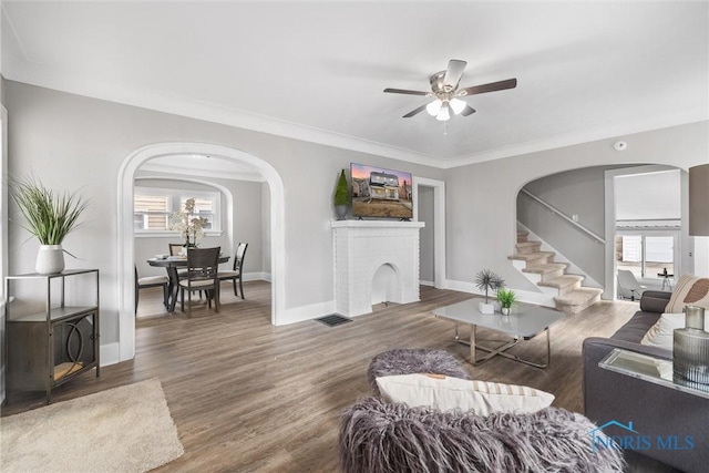 living room with ceiling fan, crown molding, dark wood-type flooring, and a healthy amount of sunlight