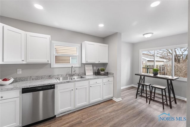 kitchen featuring sink, hardwood / wood-style flooring, dishwasher, white cabinetry, and light stone countertops