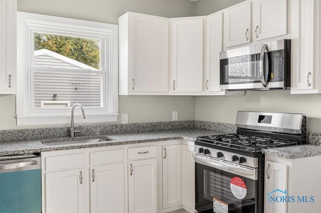 kitchen with stainless steel appliances, sink, and white cabinets