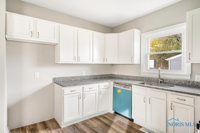 kitchen featuring sink, dark wood-type flooring, white cabinetry, dark stone countertops, and stainless steel dishwasher