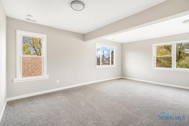 carpeted empty room featuring beam ceiling