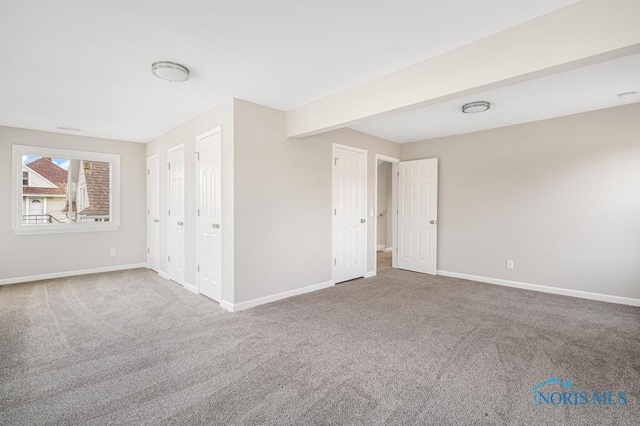 carpeted empty room with beam ceiling