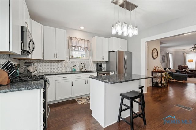 kitchen featuring sink, white cabinetry, hanging light fixtures, stainless steel appliances, and a center island