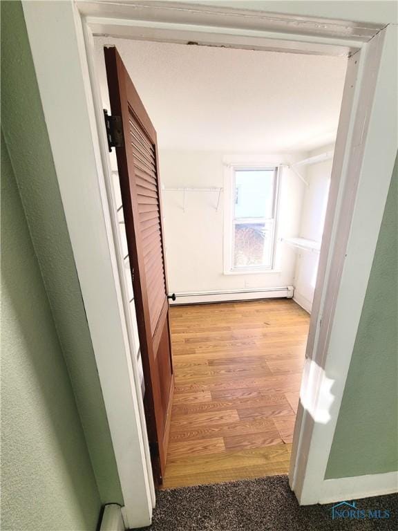 corridor featuring light wood-type flooring and baseboard heating