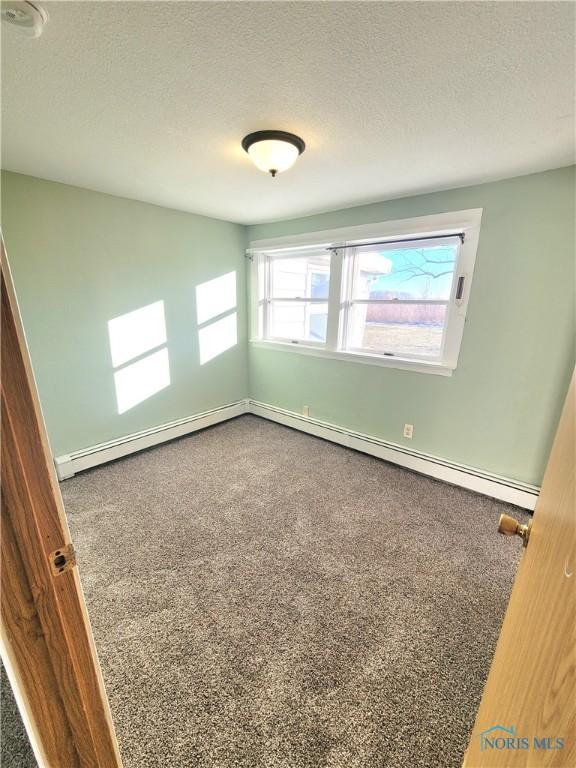 carpeted spare room featuring a baseboard radiator and a textured ceiling