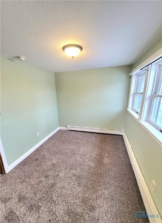 carpeted spare room featuring a textured ceiling and baseboard heating