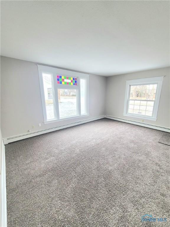 unfurnished room with a baseboard heating unit and carpet floors