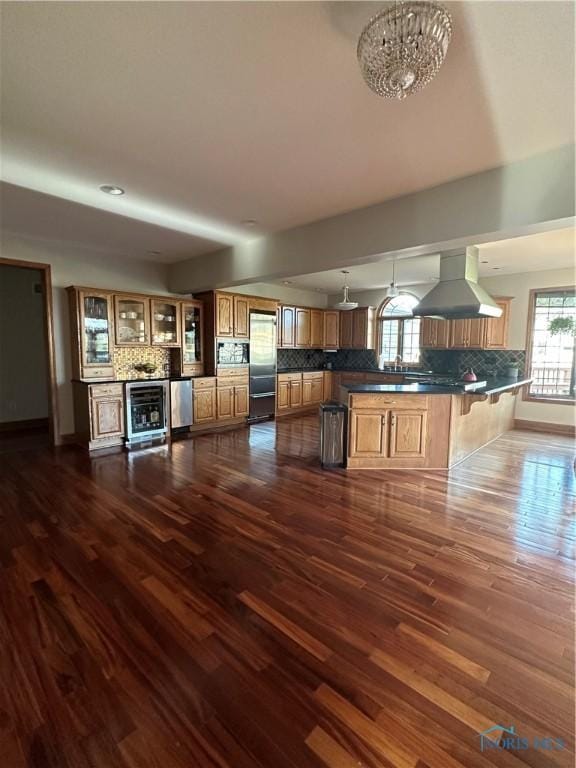 kitchen with tasteful backsplash, island range hood, pendant lighting, stainless steel appliances, and beverage cooler