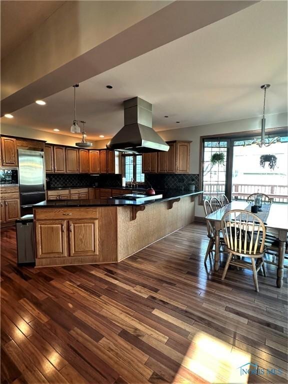 kitchen with island exhaust hood, pendant lighting, built in appliances, and kitchen peninsula