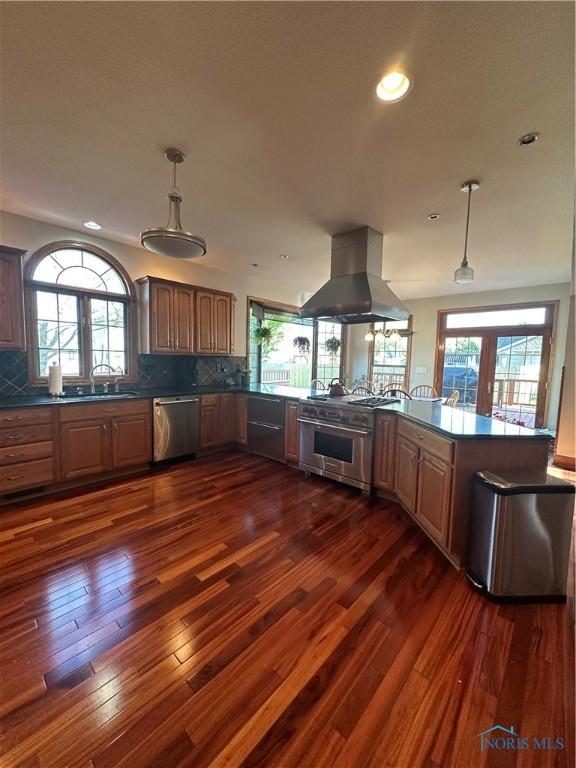 kitchen with tasteful backsplash, appliances with stainless steel finishes, island range hood, and kitchen peninsula