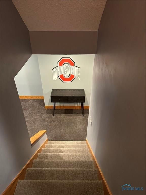 stairs with carpet and a textured ceiling