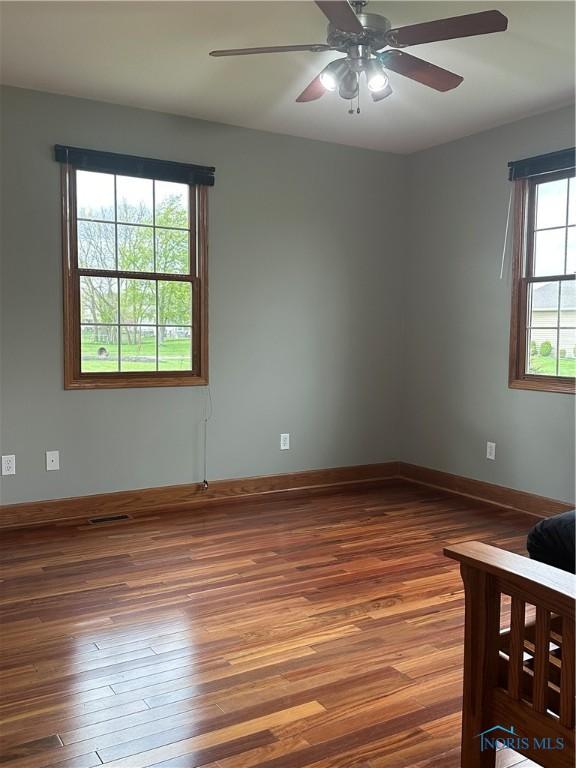 empty room featuring ceiling fan, a healthy amount of sunlight, and hardwood / wood-style floors