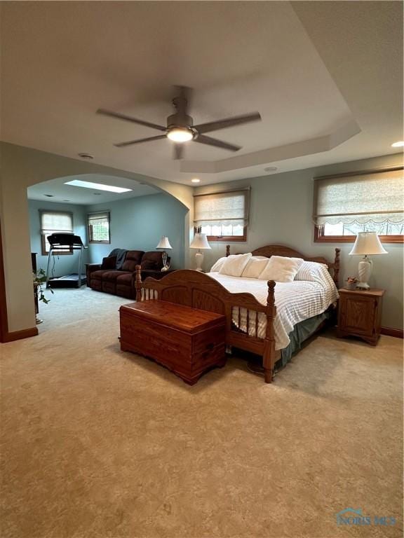 carpeted bedroom featuring ceiling fan and a tray ceiling