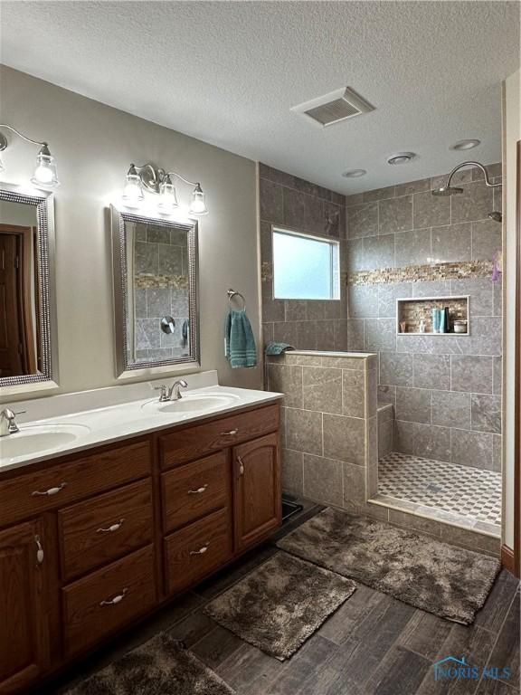 bathroom featuring vanity, a tile shower, and a textured ceiling