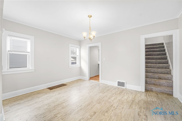 unfurnished room with wood-type flooring, ornamental molding, and a notable chandelier