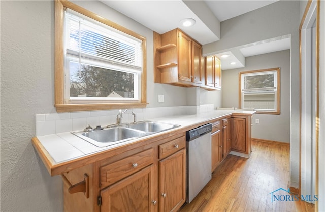 kitchen with a breakfast bar, sink, stainless steel dishwasher, kitchen peninsula, and light hardwood / wood-style floors