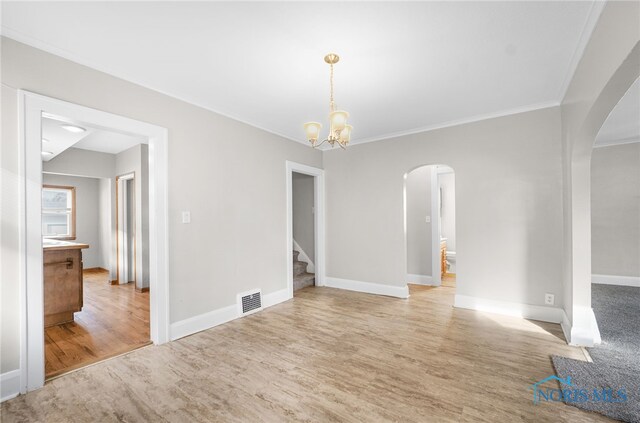 empty room featuring a notable chandelier, hardwood / wood-style flooring, and ornamental molding