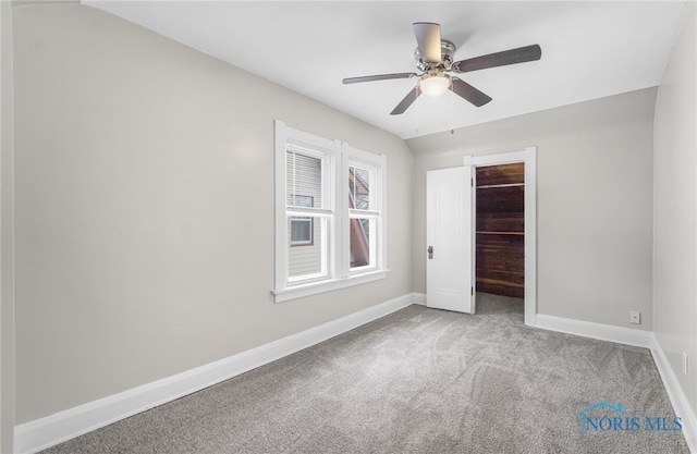 unfurnished bedroom featuring ceiling fan, vaulted ceiling, carpet flooring, a walk in closet, and a closet