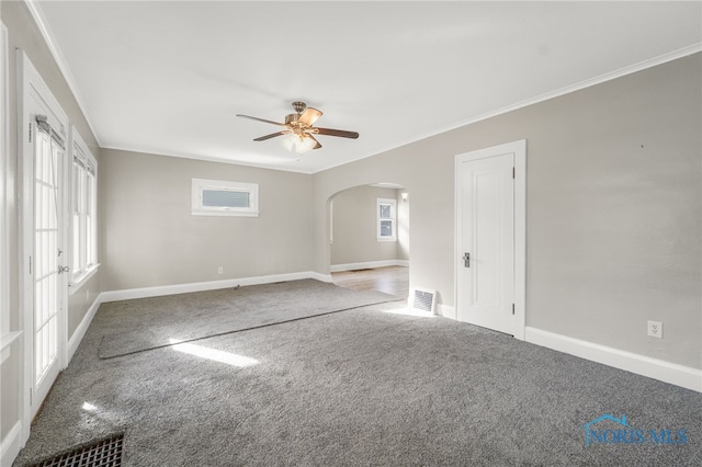 empty room with crown molding, ceiling fan, carpet, and a wealth of natural light