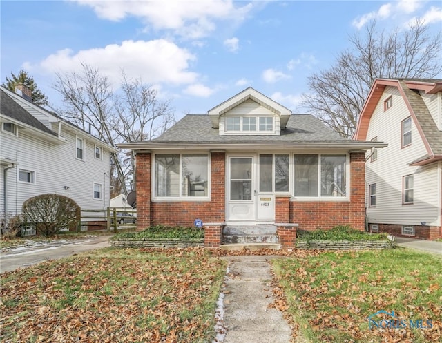 bungalow with a front lawn and a sunroom