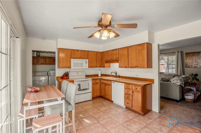 kitchen featuring ceiling fan, separate washer and dryer, sink, and white appliances