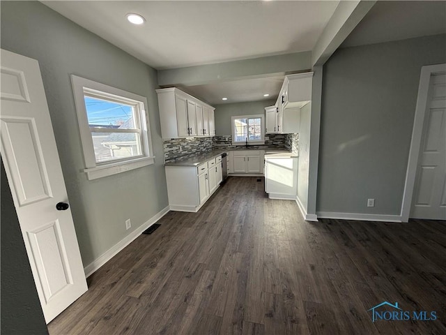 kitchen featuring dark wood-type flooring, white cabinets, and decorative backsplash