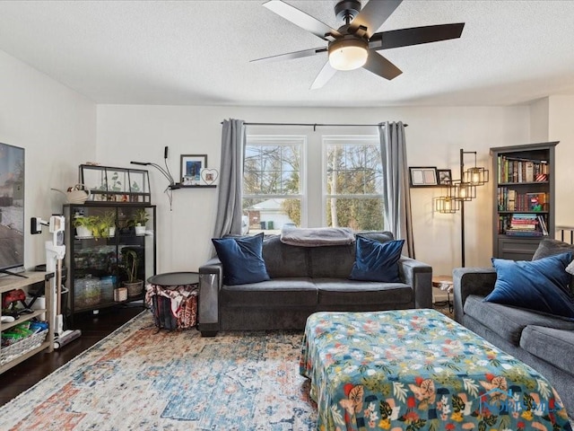 living room with dark wood-type flooring, ceiling fan, and a textured ceiling