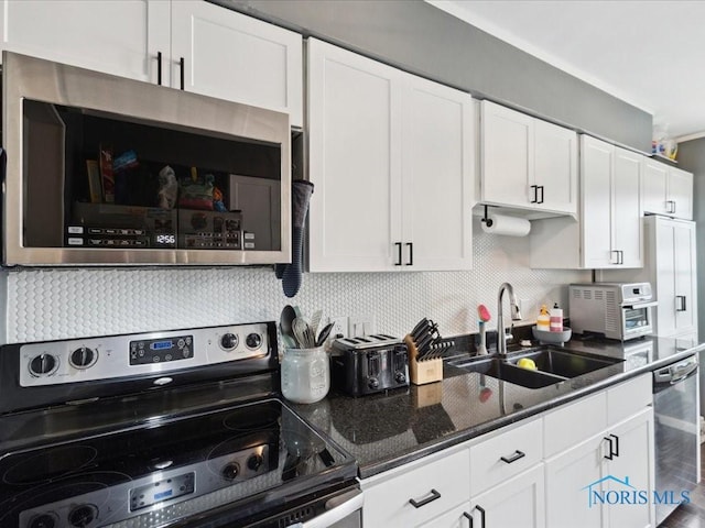 kitchen with tasteful backsplash, appliances with stainless steel finishes, sink, and white cabinets