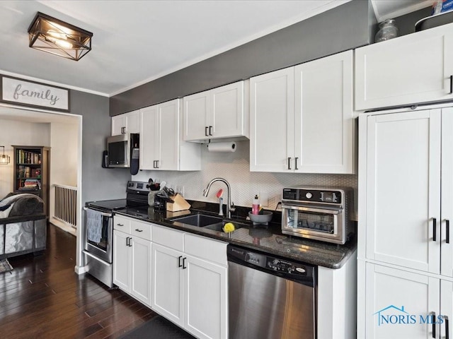 kitchen featuring appliances with stainless steel finishes, sink, dark wood-type flooring, and white cabinets