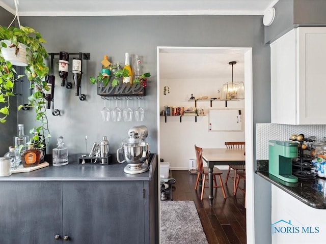 bar with dark hardwood / wood-style flooring, backsplash, white cabinetry, and hanging light fixtures