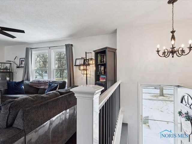 living room featuring ceiling fan with notable chandelier and a textured ceiling