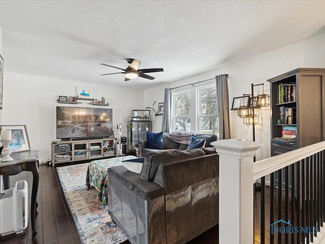 living room with ceiling fan, dark wood-type flooring, and a textured ceiling