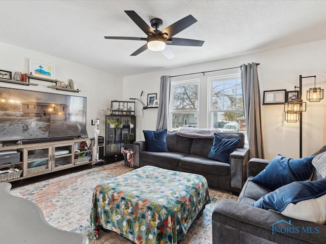 living room featuring ceiling fan and a textured ceiling