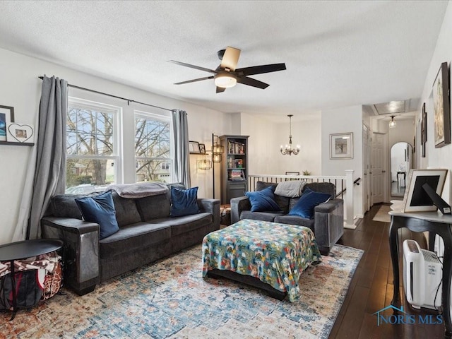 living room with dark wood-type flooring, ceiling fan with notable chandelier, and a textured ceiling