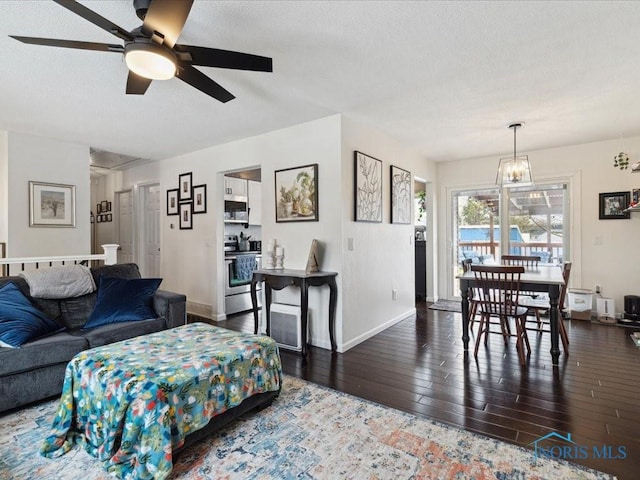 living room with ceiling fan with notable chandelier, dark hardwood / wood-style floors, and a textured ceiling