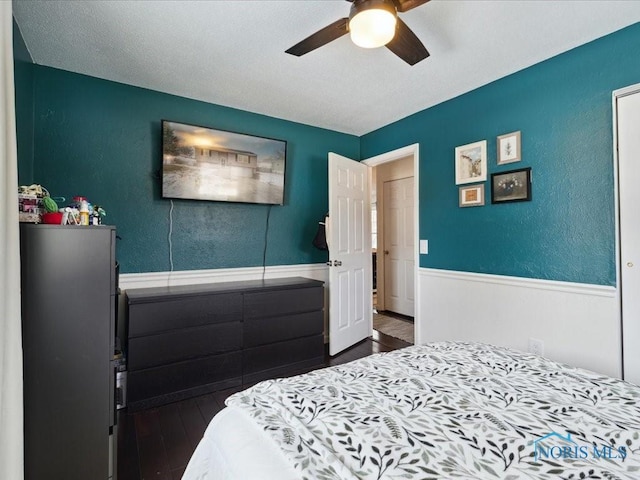 bedroom featuring dark hardwood / wood-style floors, a textured ceiling, and ceiling fan