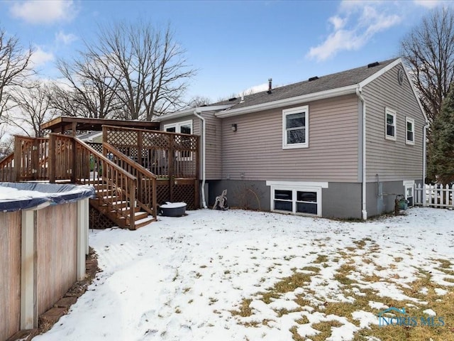 snow covered rear of property featuring a deck