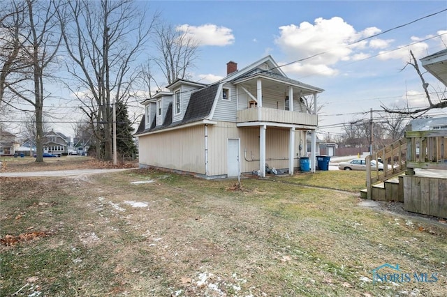 view of property exterior featuring a balcony and a lawn