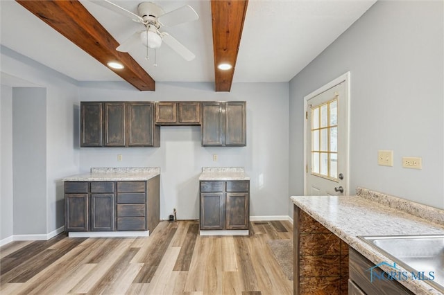 kitchen with light hardwood / wood-style flooring, ceiling fan, dark brown cabinetry, light stone counters, and beamed ceiling